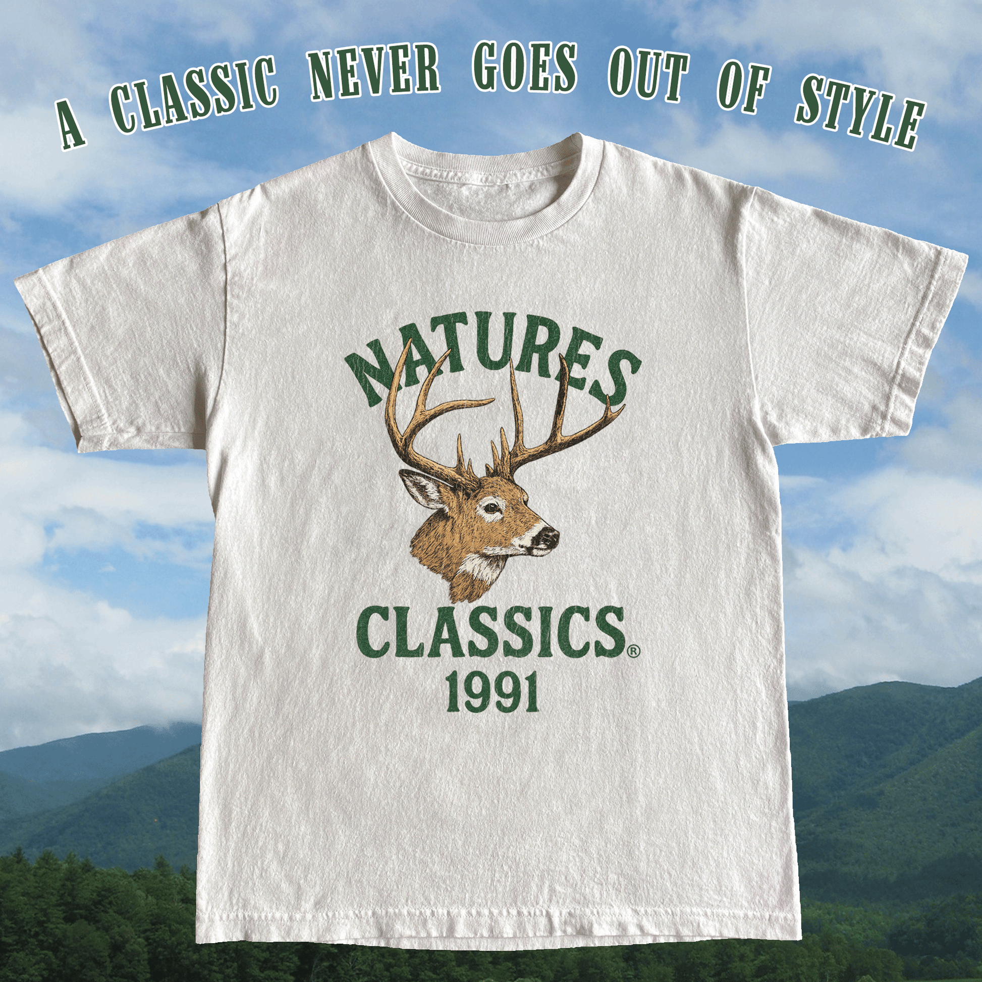 White t-shirt with deer graphic and text 'Natures Classics 1991' against a mountainous background