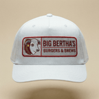 White cap with 'Big Bertha's Burgers & Brews' logo on a beige background