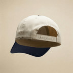 Two-tone cap with beige front and navy back on a beige background