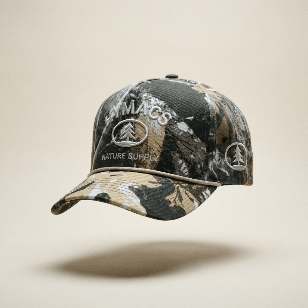 Camouflage baseball cap with 'Macs Nature Supply' branding on a beige background
